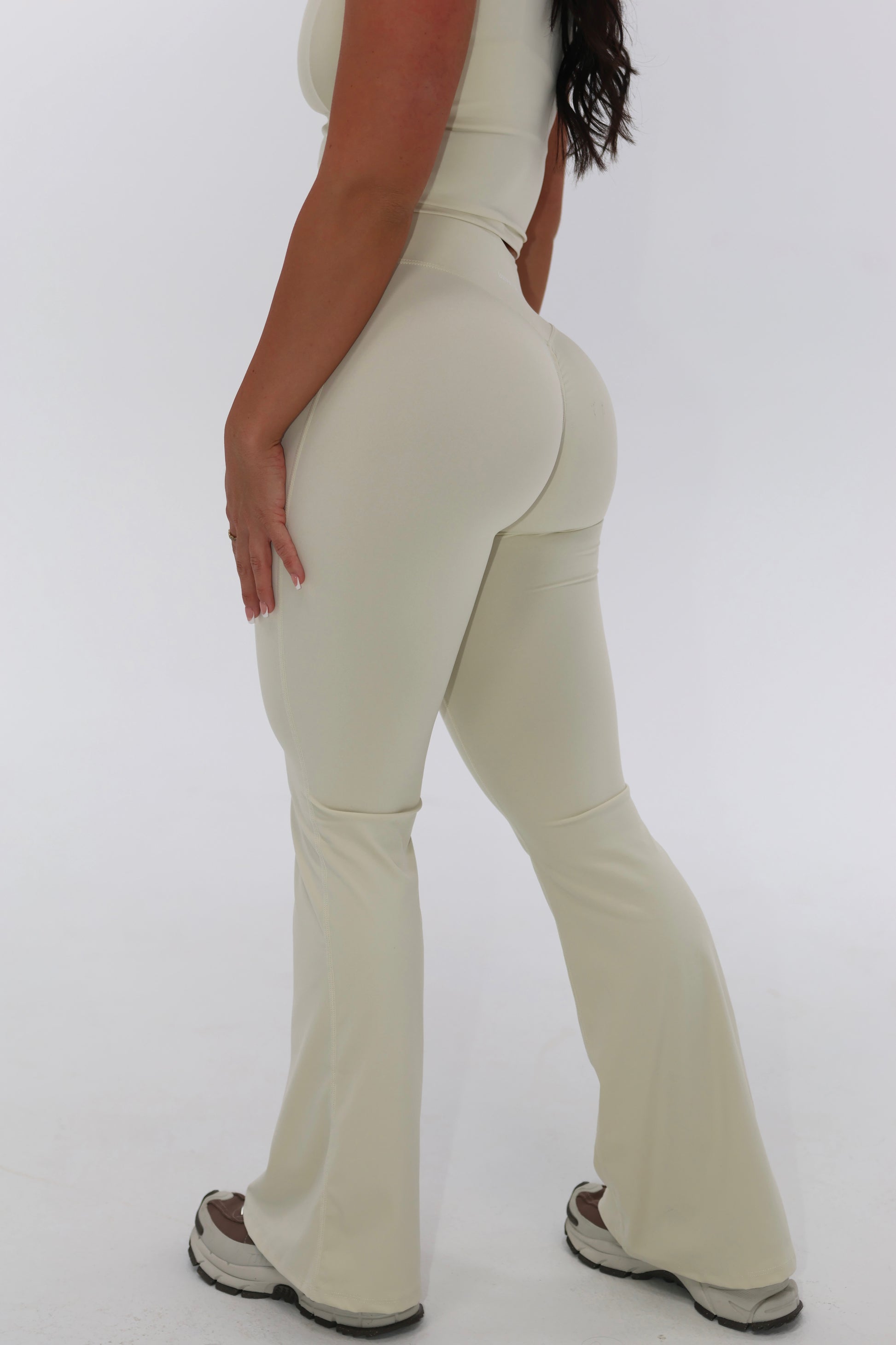 Person wearing beige flared pants on a white background