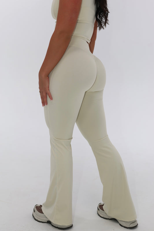 Person wearing beige flared pants on a white background
